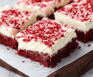 Delicious red velvet cookie bars with cream cheese frosting on a white plate.
