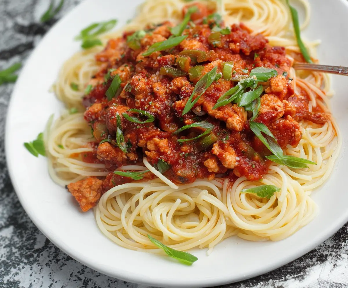 Delicious veggie-loaded ground chicken spaghetti sauce in a rustic bowl, garnished with fresh herbs.