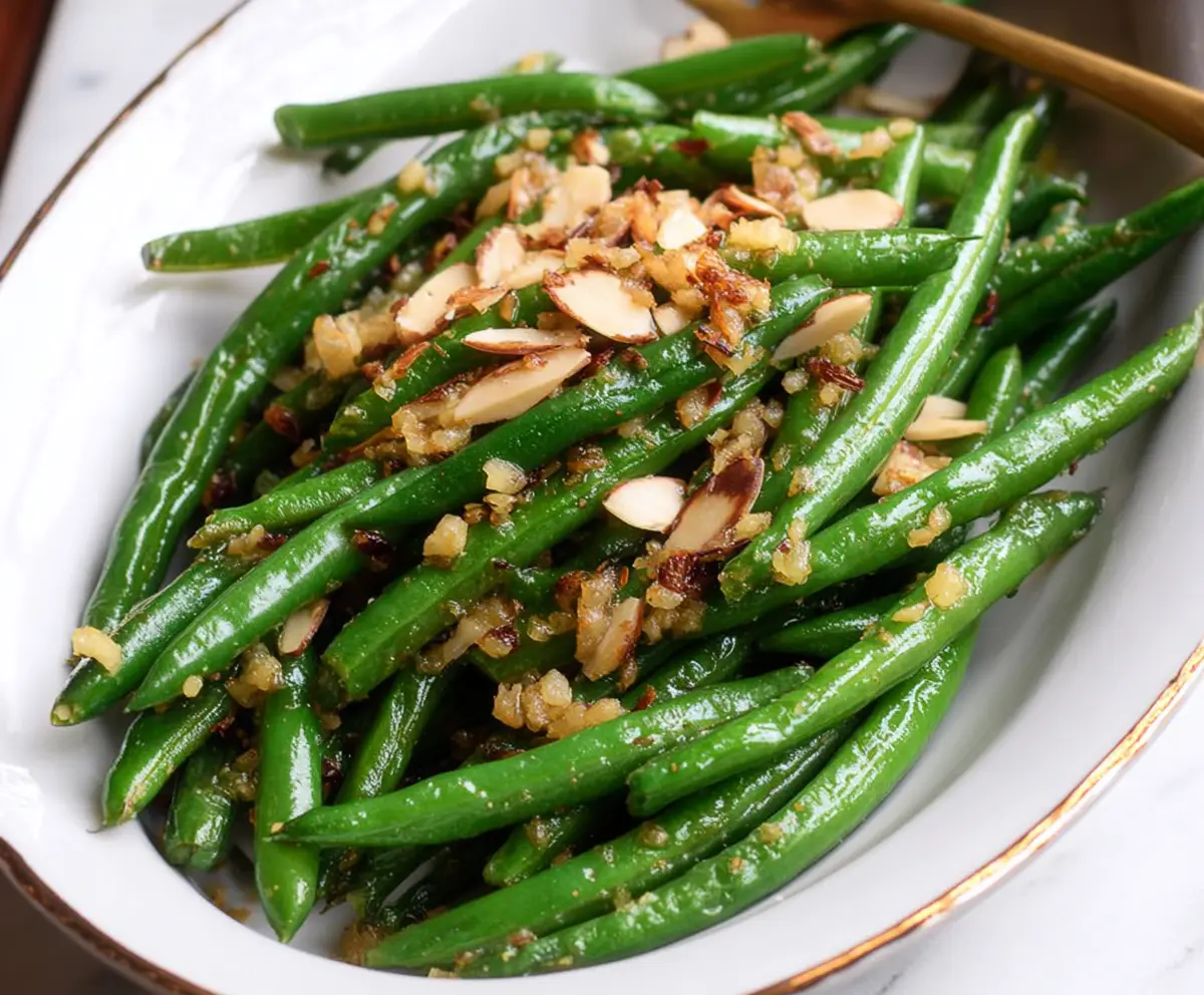 Delicious Green Bean Almondine garnished with toasted almonds on a white plate.