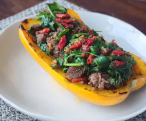 Delicata squash stuffed with venison, goji berries, and spinach, a nutritious and colorful dish.