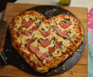 Delicious homemade Valentine Pizza with heart-shaped toppings and vibrant colors.